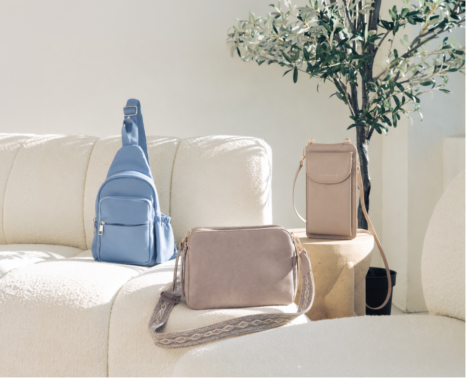 Three bags on a beige sofa with a neutral background